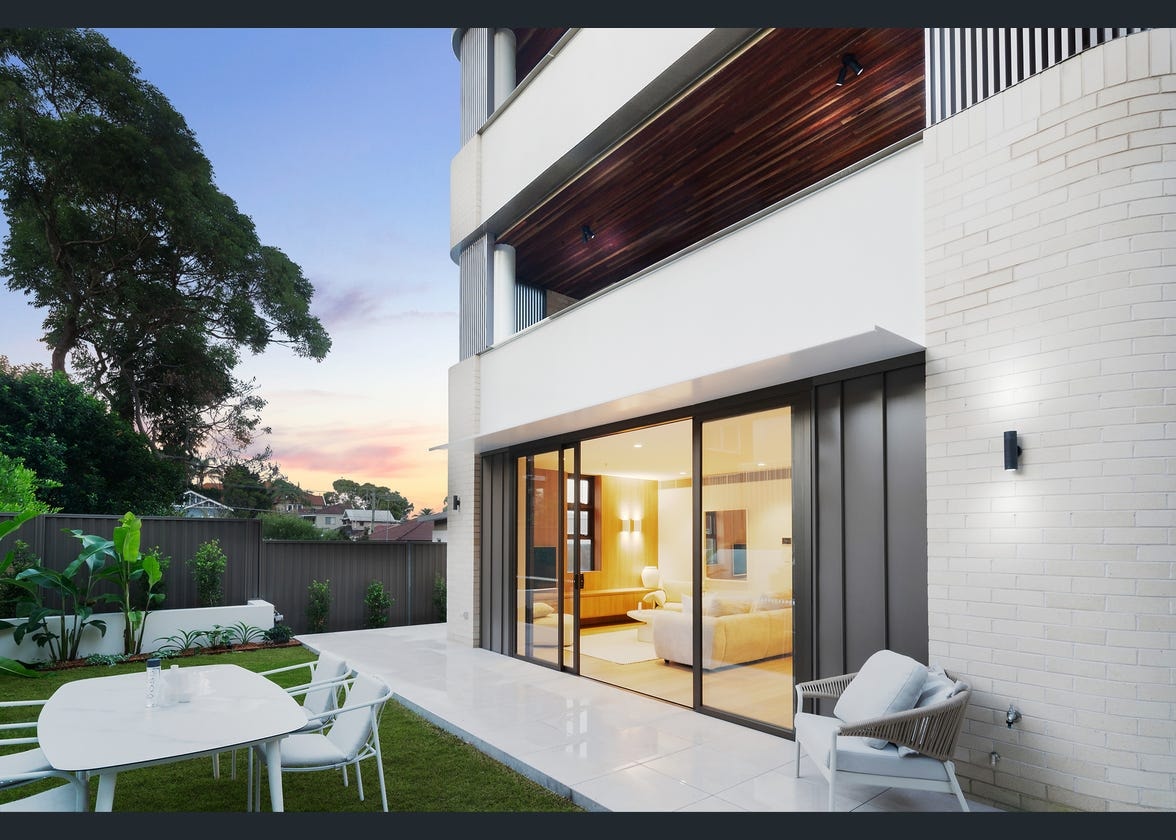 Residential exterior at dusk with sliding glass doors and garden